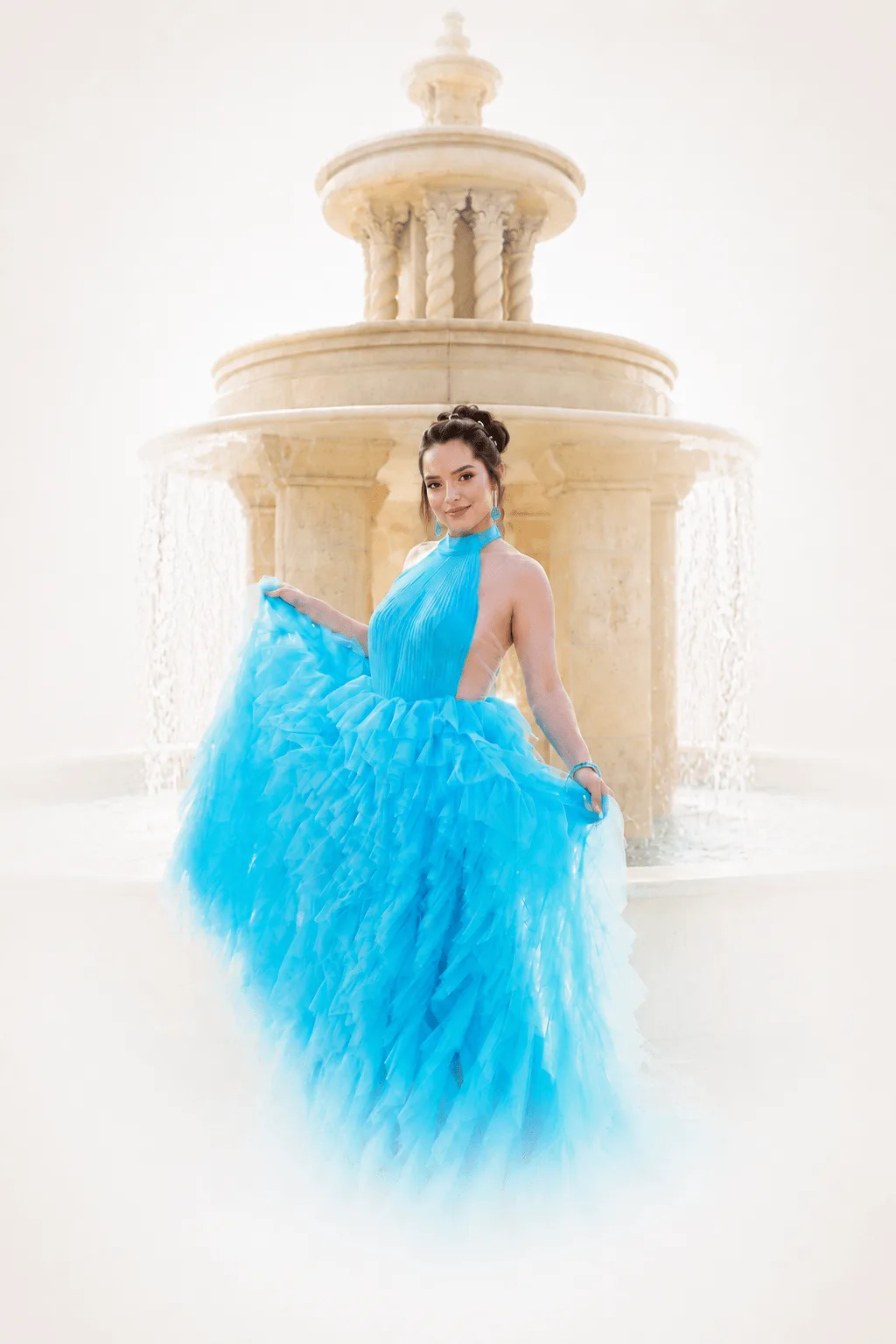 Quinceanera in a gorgeous royal blue gown standing next to an elegant fountain