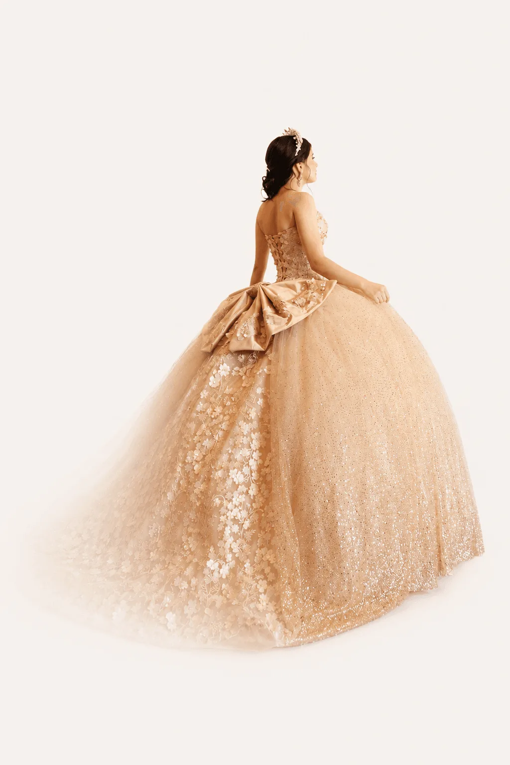 Quinceañera posando con un espectacular vestido dorado mostrando bordados intrincados